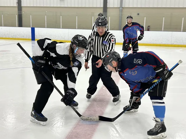 Two players facing off as the referee prepares to drop the puck