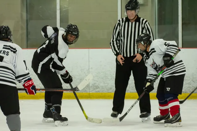 A referee dropping the puck between two players at centre ice