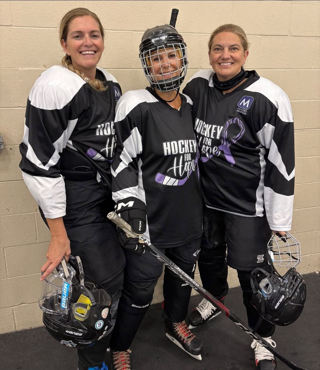 Three players in Hockey for Hope jerseys standing together in the arena hallway