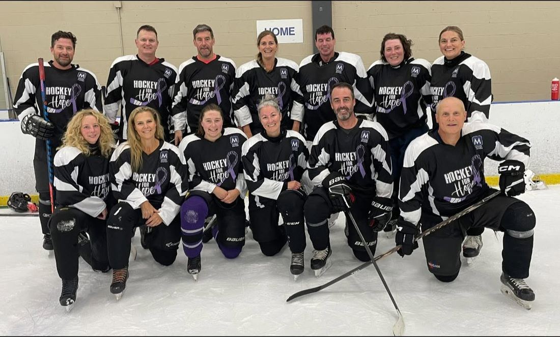 A full team in Hockey for Hope jerseys posing on the ice