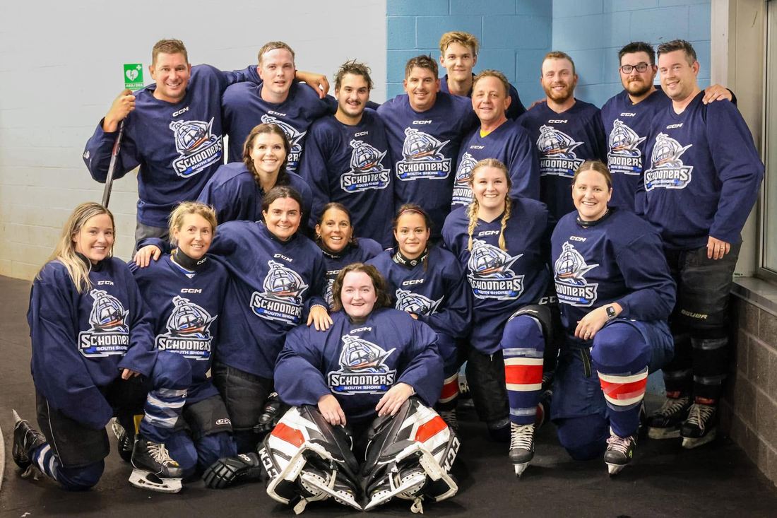A large co-ed team in navy jerseys gathered for a group photo