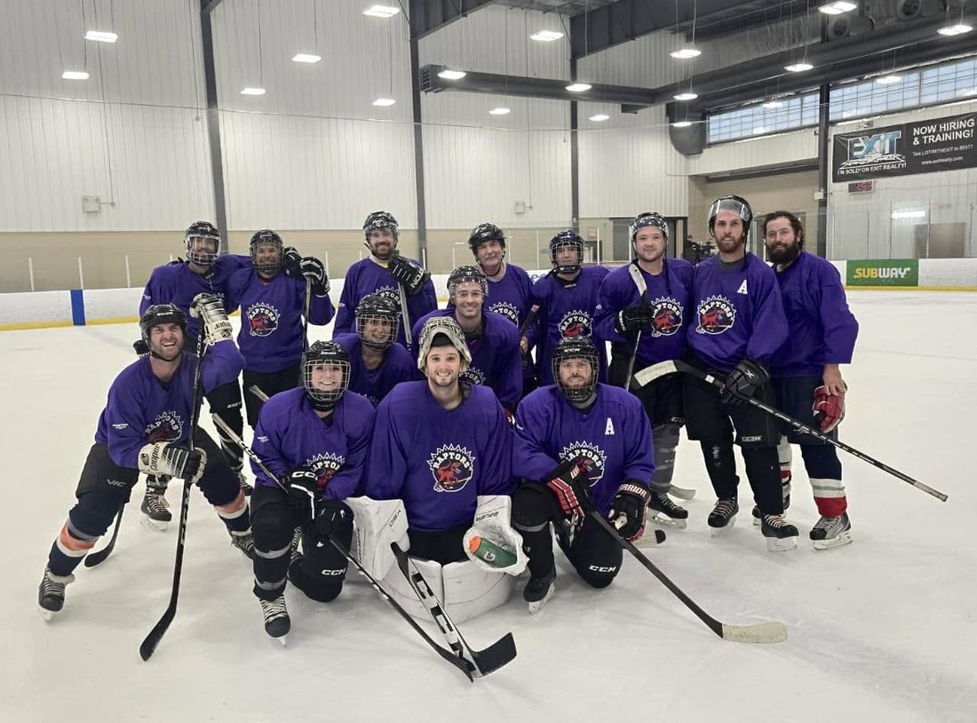 A co-ed team in purple Hockey for Hope jerseys posing together on the ice after a game