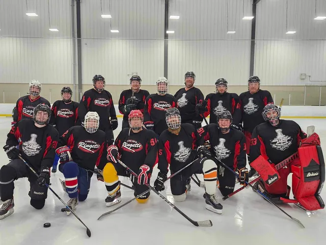 Two teams in red and black gathered together on the ice after a game