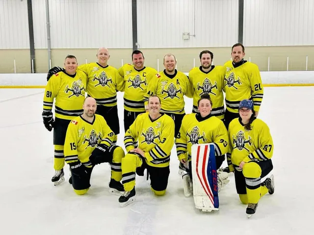 A team in yellow jerseys kneeling for a photo on the ice